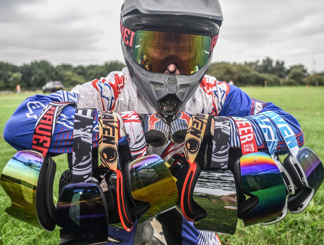 Motocross rider holding various goggles on his arms