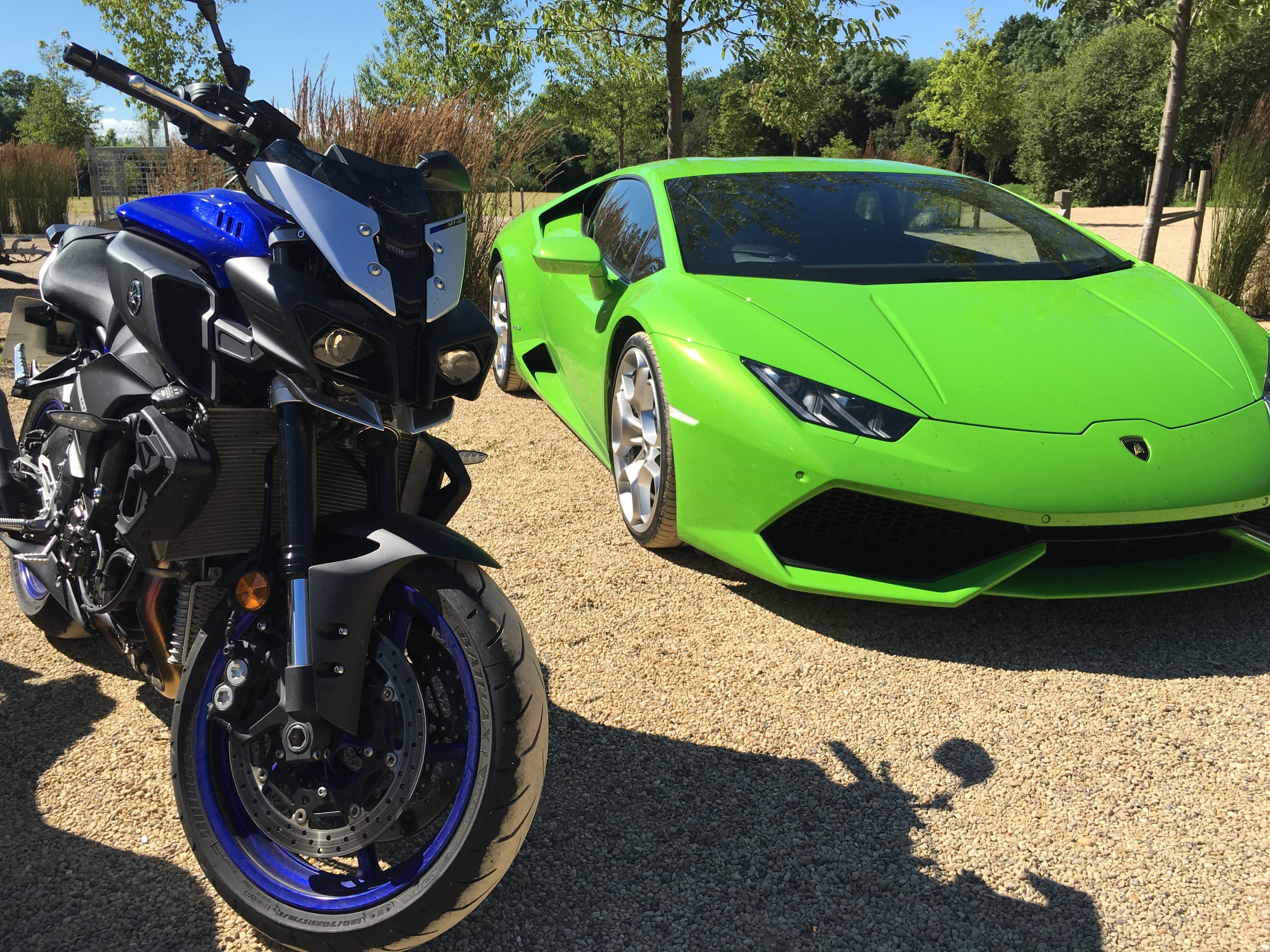 Blue Yamaha MT-10 motorbike next to a bright green Lamborghini