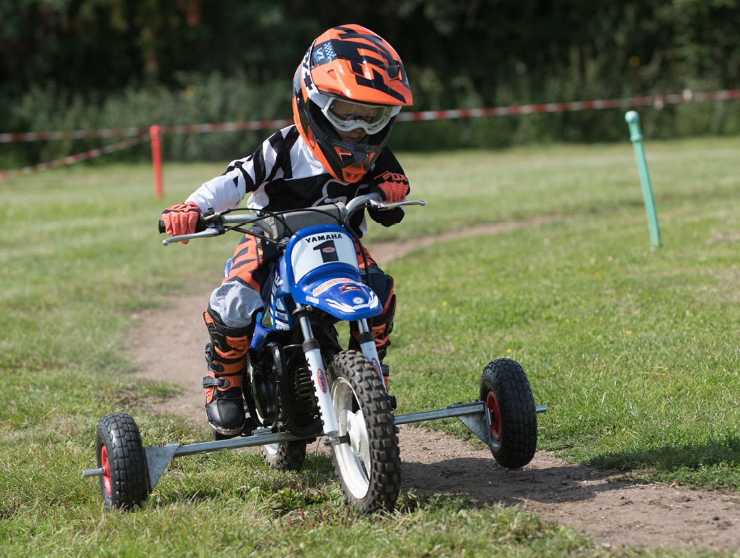 Junior motocross rider learning with stabilisers