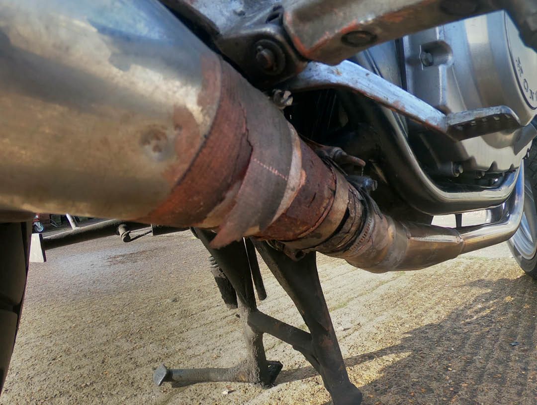 Close up of the underside of a rusty motorcycle exhaust