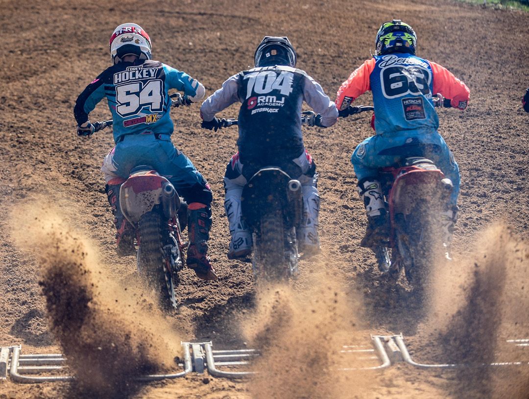 Rear view of three motocross racers leaving the start line