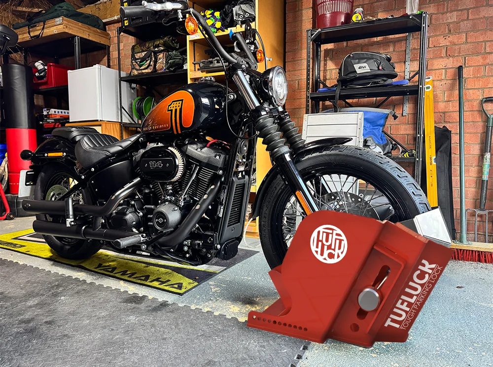 Harley-Davidson motorcycle secured in a workshop garage using a red TufLuck Tough Motorcycle Parking Lock.