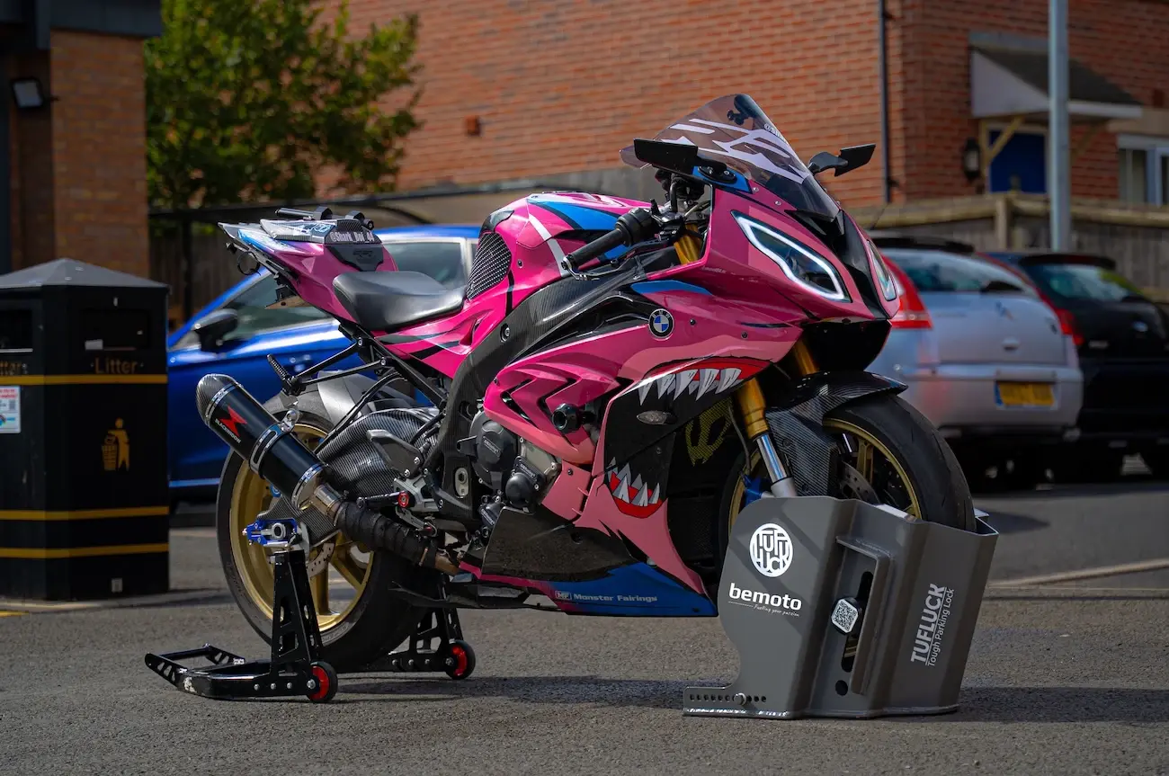 High performance sports motorcycle secured with a TufLuck heavy duty parking lock featuring BeMoto branding, parked in an urban residential setting.