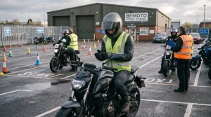 A motorcyclist wearing a hi-vis vest and full protective gear adjusts their glove while seated on a naked motorcycle at BeMoto Riding School.