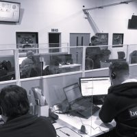 About BeMoto – Moto Broking House A black and white photo of a large contact centre with banks of desks. There are figures sat at the desks wearing headsets and handling customer calls. The office is decorated with pictures of motorcycles.